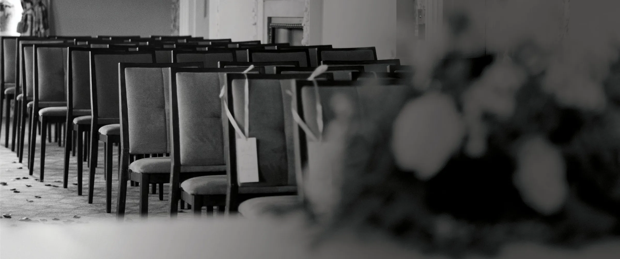 Rows of wedding ceremony chairs in black and white, with soft blurred flowers in the foreground