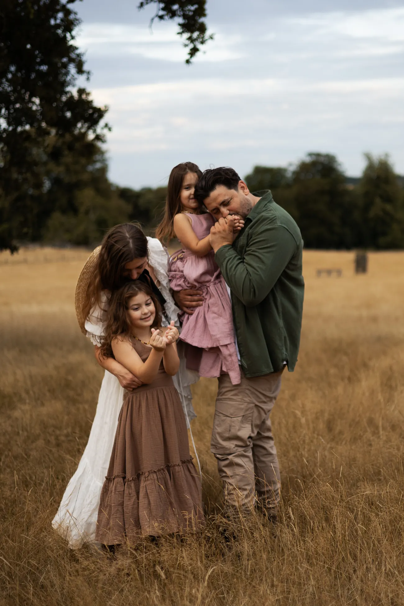 A family of four laughing and dancing in a golden field